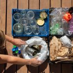 A woman sorts plastic bottles on a wooden deck, organizing them for recycling or disposal